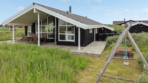 Une maison moderne dotée d’un patio couvert, de grandes fenêtres et d’une terrasse en bois.