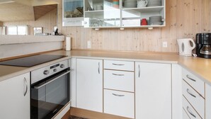 Une cuisine moderne avec des meubles blancs, un four encastré et une machine à café posée sur le plan de travail.