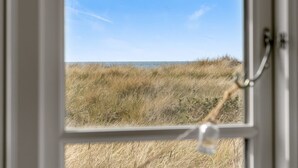 Una ventana con vista a un campo cubierto de hierba y un cielo despejado.