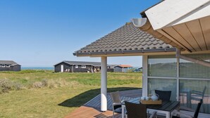 Una terraza con mesa y sillas, con vistas a un espacio verde con casas al fondo.