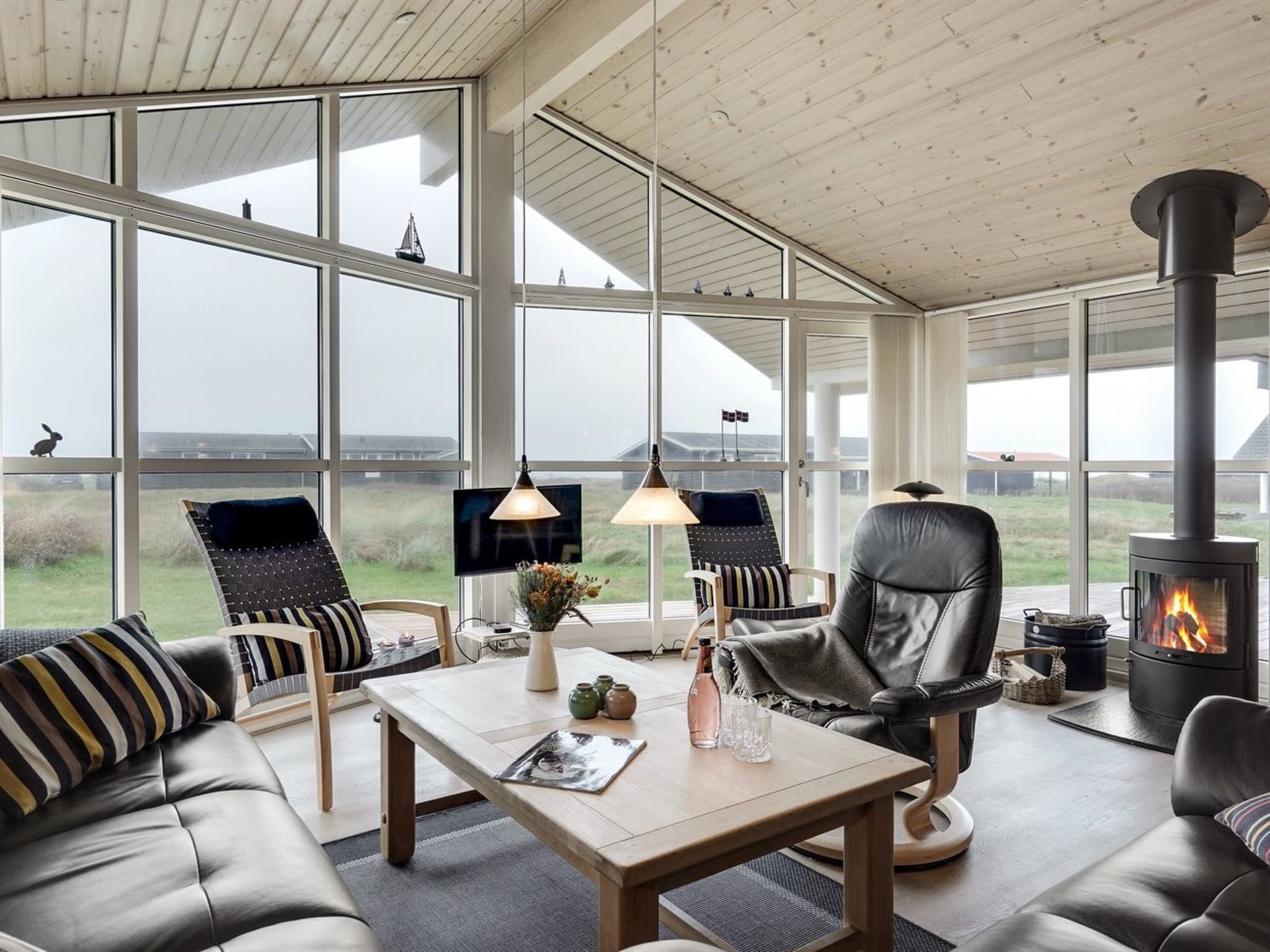 A spacious living area with large windows, a fireplace, and comfortable seating.