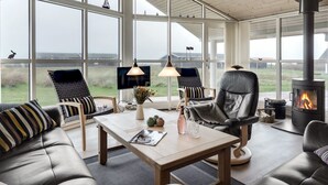 Un amplio salón con ventanas grandes, chimenea y un mobiliario cómodo.