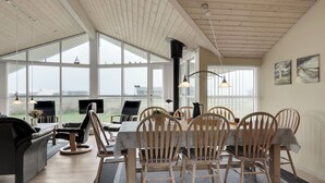 Un comedor con una mesa grande y sillas, un televisor y vistas al exterior.