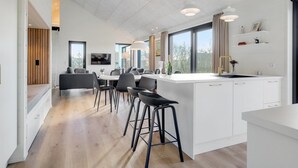 Een moderne keuken met een centraal eiland, barstoelen en een eethoek met een televisie.