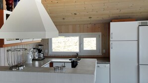 Une cuisine moderne dotée d’un grand îlot central, de meubles blancs et d’un plafond en bois.