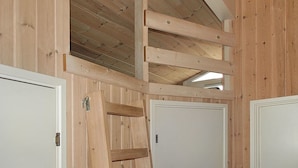 Un intérieur en bois avec un plafond incliné, des murs en bois et des portes blanches.
