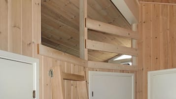 Un intérieur en bois avec un plafond incliné, des murs en bois et des portes blanches.