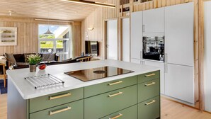 A modern kitchen with a central island, white cabinets, and a view of the outdoors. - "Ellen" - 289m from the sea by Interhome (Hjørring)