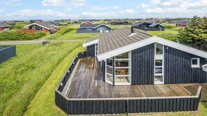 A modern house with a large deck, surrounded by a grassy area and other houses. - "Ellen" - 289m from the sea by Interhome (Hjørring)