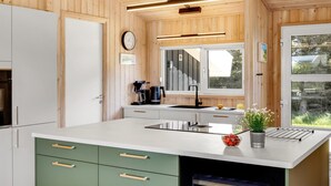 A modern kitchen with wooden walls, a large window, and a built-in wine cooler. - "Ellen" - 289m from the sea by Interhome (Hjørring)