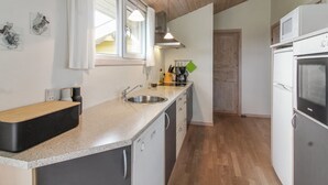 Eine moderne Küche mit Holzboden, einer Edelstahl-Spüle und einem eingebauten Backofen.