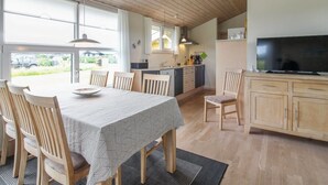 Eine geräumige Küche mit Holdekor-Schränken, einem Esstisch mit Stühlen und einem großen Fernseher auf einem Schrank.