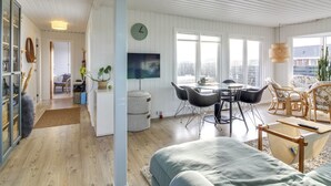 Una sala de estar moderna con comedor, ventanas amplias y vistas a la ciudad.