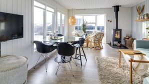 Una sala de estar moderna con comedor, chimenea y ventanas amplias que ofrecen vistas.