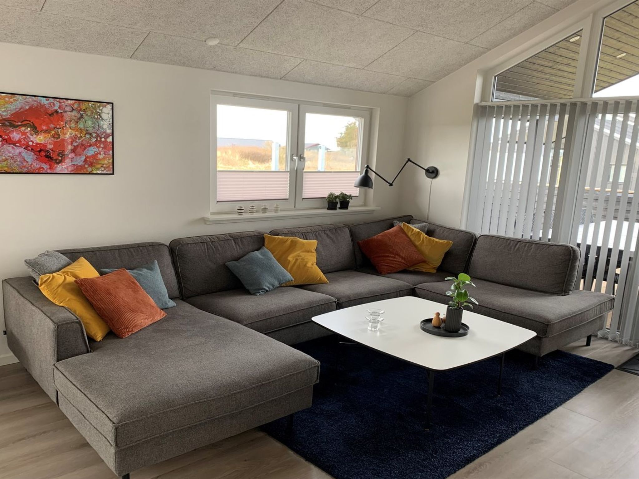 Una sala de estar moderna con un sofá seccional gris, una mesa de centro blanca y una alfombra azul.