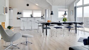 Une cuisine moderne avec des meubles blancs, un îlot central et des tabourets de bar.