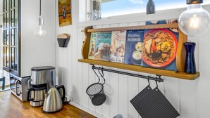 Uma cozinha com cafeteira, chaleira, suporte para panelas pendurado e um quadro de cardápio.