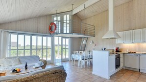 A spacious living area with a high ceiling, a balcony, and a kitchen area.