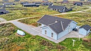 A coastal residential area with multiple houses, a clear sky, and a view of the sea.