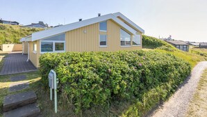 Ein modernes, zweistöckiges Haus mit geneigtem Dach, großen Fenstern und einem gepflegten Garten.