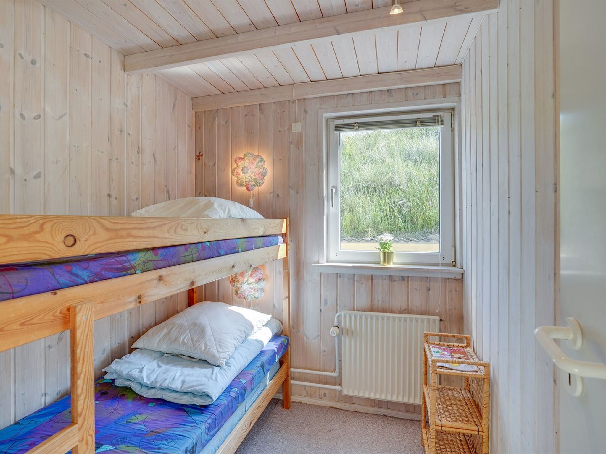 Et værelse med køjeseng, vindue, radiator og et lille bord.