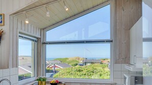 Eine moderne Küche mit großem Fenster, Holzschränken und einer Spüle aus Edelstahl.