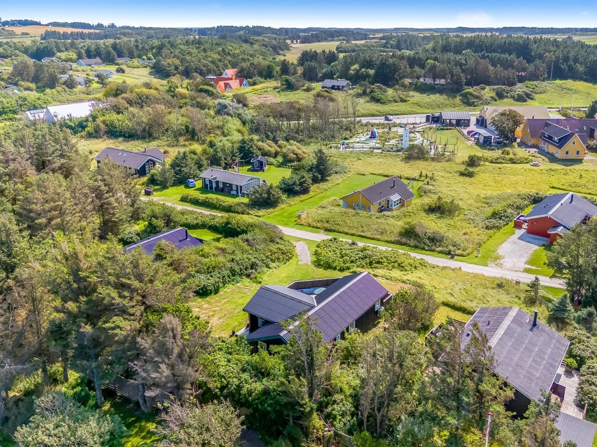 Vue aérienne d’un quartier résidentiel avec des maisons, des espaces verts et une aire de jeux.