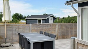 A deck with a table and chairs, surrounded by a wooden fence, and a building in the background. - "Liisi" - 500m from the sea by Interhome (Hjørring)