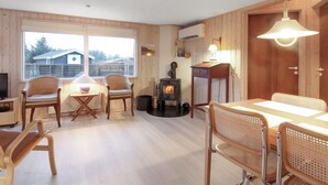 A cozy cabin interior with a wooden interior, a fireplace, a dining table, and chairs. - "Liisi" - 500m from the sea by Interhome (Hjørring)