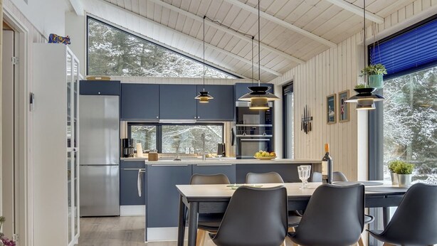 A modern kitchen with a central island, wooden flooring, and large windows.