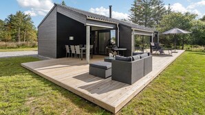 A modern house with a covered patio, outdoor seating, and a grill area.