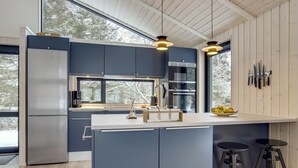 A modern kitchen with dark blue cabinets, stainless steel appliances, and a large island with stools.