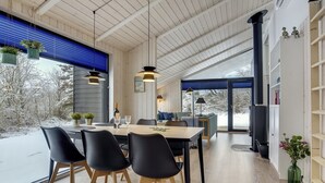 A modern dining area with a wooden table, black chairs, and hanging plants.