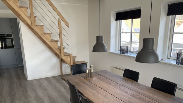 Eine moderne Küche mit grauen Schränken und einer Holztreppe.