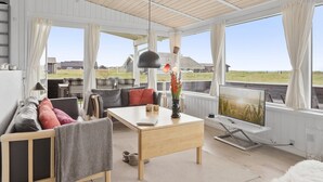 Ein geräumiges Wohnzimmer mit Sofa, Couchtisch und Blick auf die Landschaft durch große Fenster.