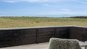 Eine Terrasse mit Blick auf ein Grasfeld und das Meer.