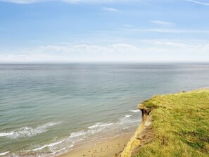 Un paysage côtier avec une falaise herbeuse et une mer calme.