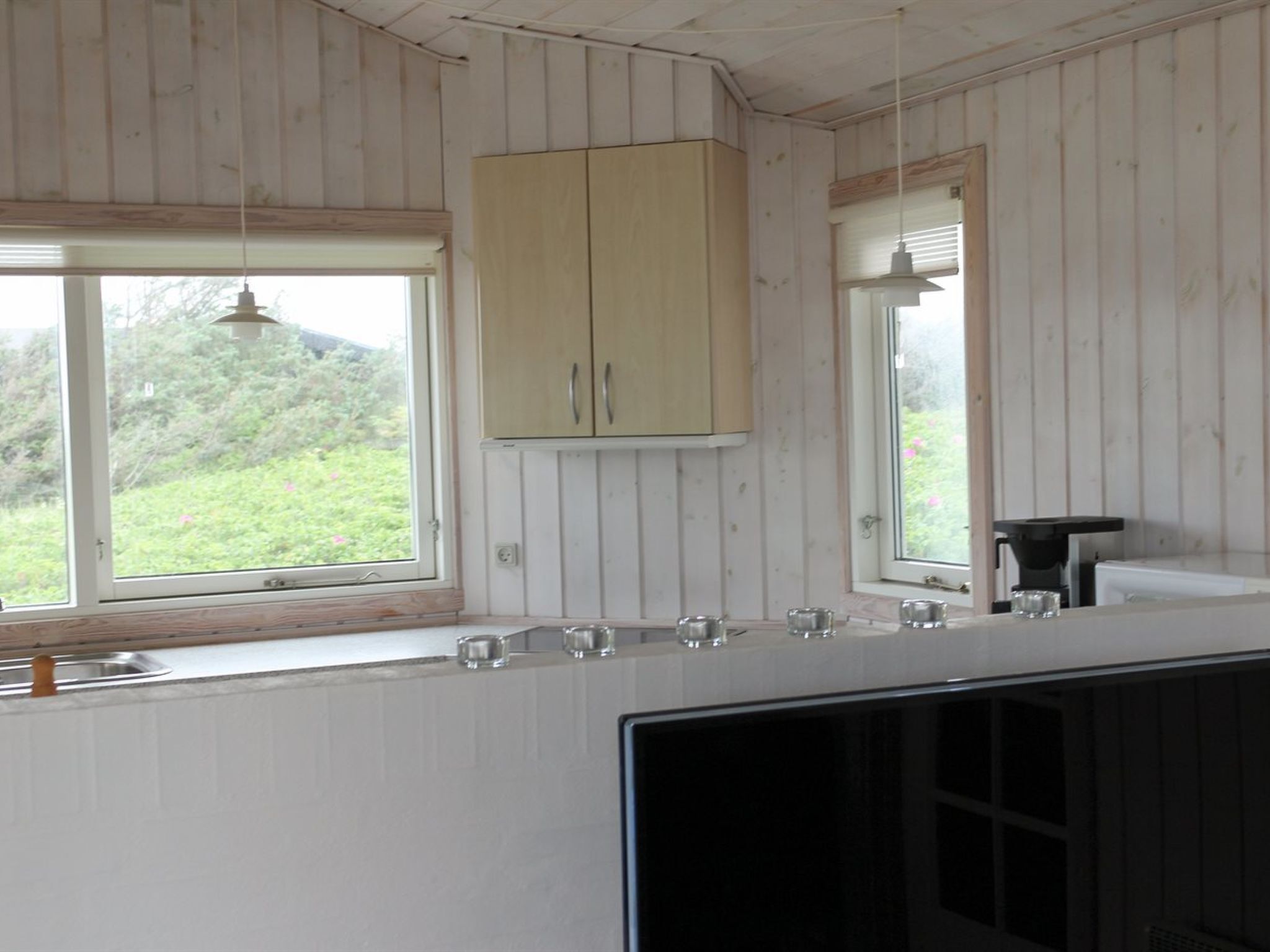Une cuisine avec des murs en bois, une fenêtre et un évier.
