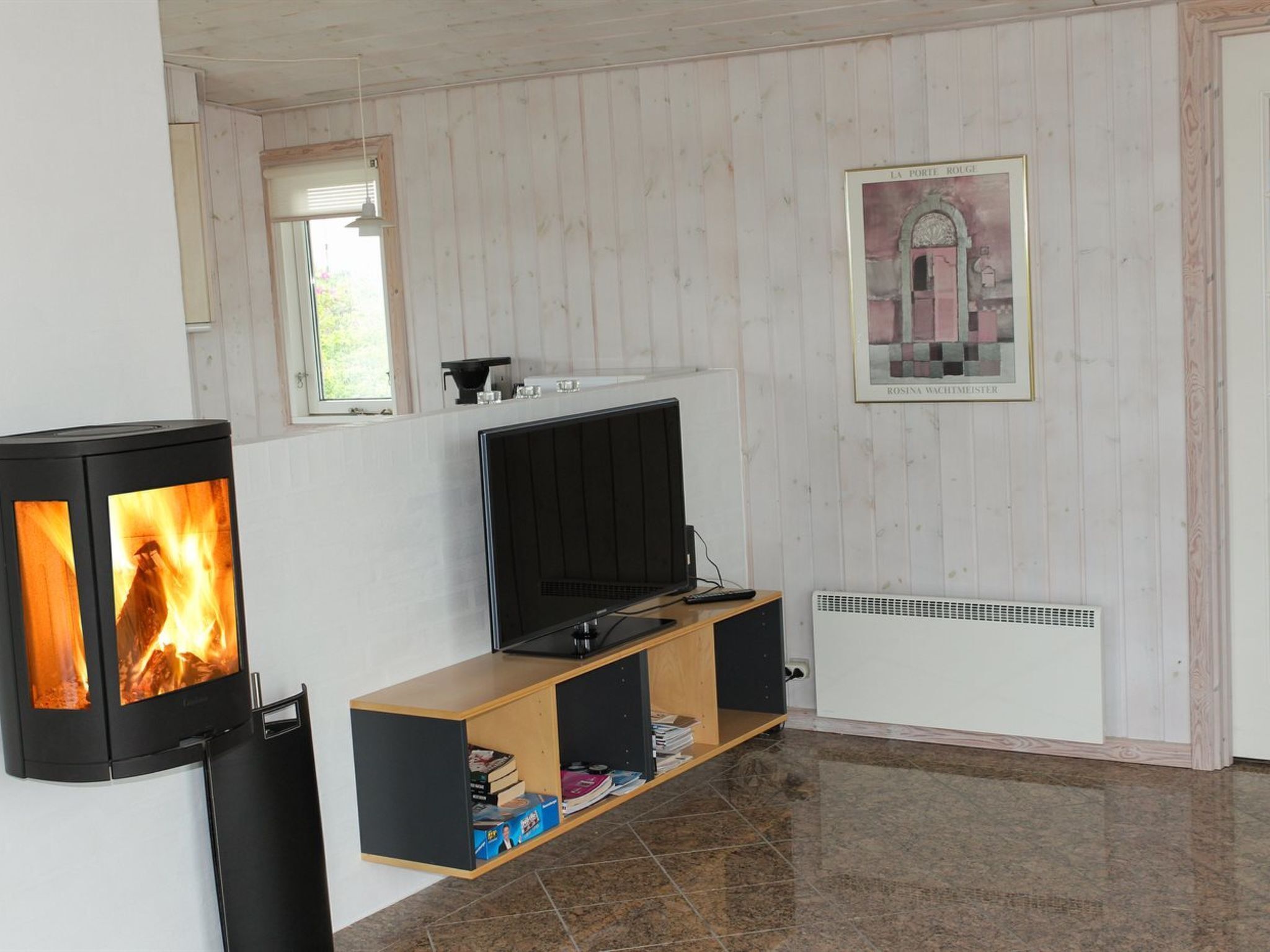 Een kamer met een televisie op een houten standaard, een open haard met vlammen, een ingelijst schilderij aan de muur en een raam met jaloezieën.