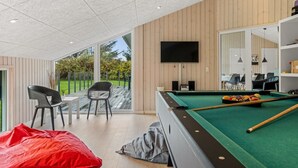 Un espace intérieur moderne comprenant une table de billard, un coin salon et un téléviseur.
