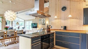 A modern kitchen with a central island, built-in oven, and a wooden ceiling. - "Arlett" - 950m from the sea by Interhome (Fjerritslev)