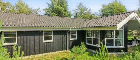 A single-story house with a dark exterior, a tiled roof, and a covered porch area.