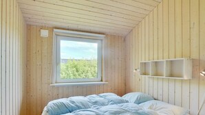 Een slaapkamer met een bed, een raam en een plank.