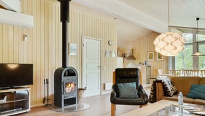 Een gezellige woonkamer met een houtkachel, een televisie en een comfortabele zithoek.