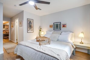 A bedroom with a bed, bedside tables, a ceiling fan, and wall art. - The Stockyard Exchange (River Oaks)