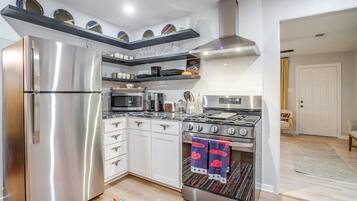 A modern kitchen with stainless steel appliances, white cabinetry, and a patterned rug.