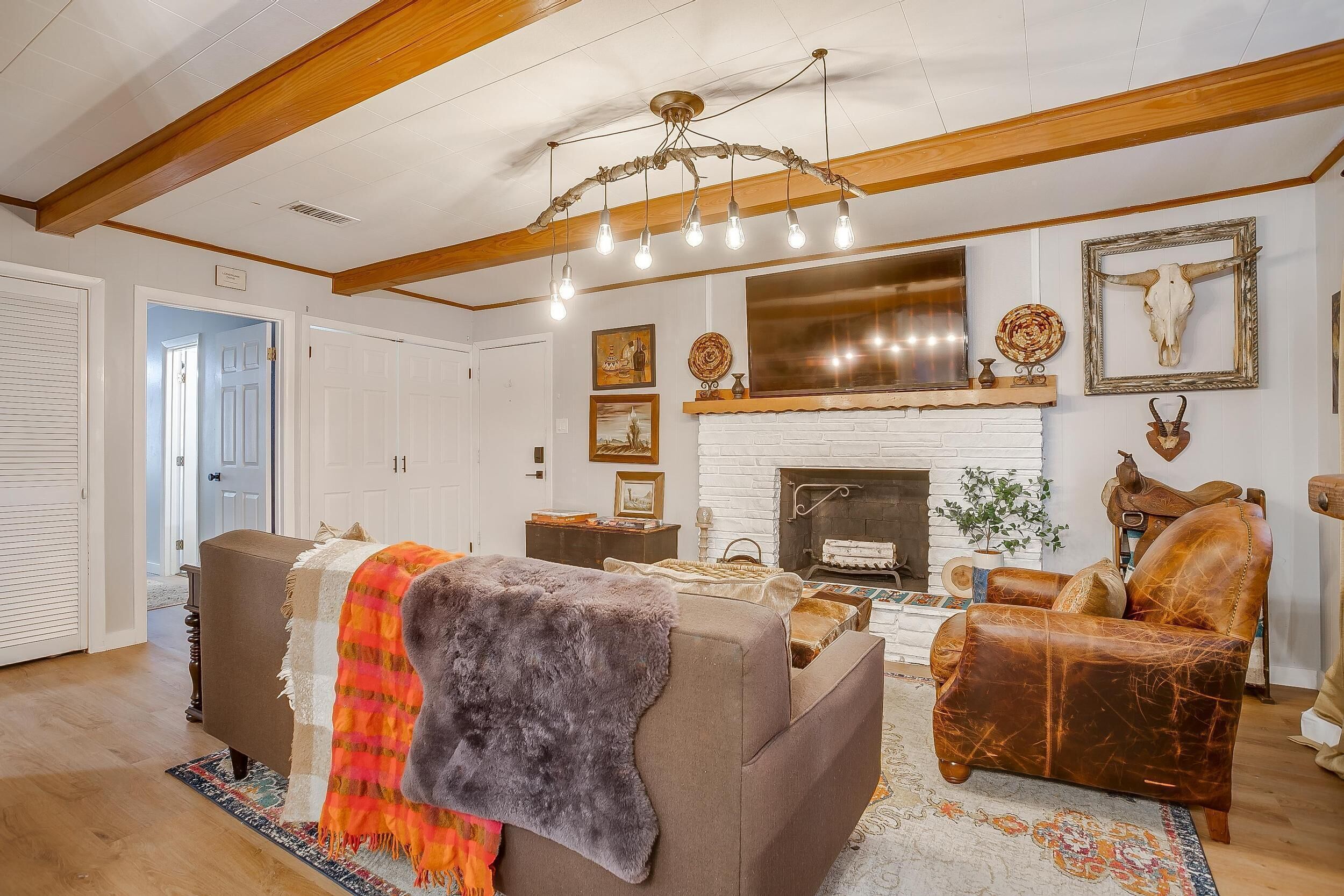 A living room with a fireplace, a sofa, a leather armchair, and a chandelier.
