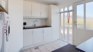 A modern kitchen with white cabinetry, a black countertop, and a built-in dishwasher.