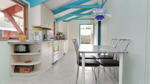 Une cuisine moderne avec des meubles blancs, un plan de travail en marbre et un coin repas comprenant une table et des chaises.
