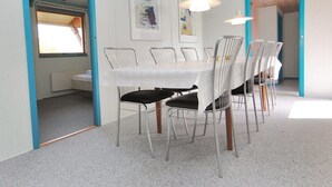 Un espace repas avec une table blanche, des chaises en métal et des luminaires suspendus.
